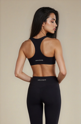 Woman wearing a black sports bra and leggings with 'COPIAS STUDIOS' branding on a beige background